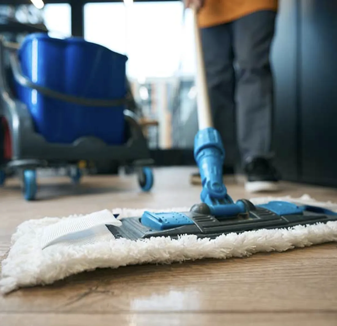 Personal de Magik Clean trapeando un piso de madera con mopa profesional y carro de aseo